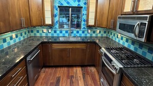 A kitchen with wooden cabinets, a stainless steel microwave, and a tiled backsplash. - Riverfront Retreat - Waterfront Views & 2 Decks (Portland)