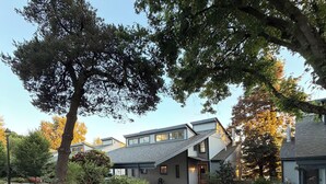 A modern building with a sloped roof, a covered driveway, and a well-maintained garden area. - Riverfront Retreat - Waterfront Views & 2 Decks (Portland)