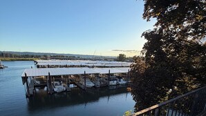 A docked boat marina with multiple boats, a clear sky, and a view of a distant cityscape. - Riverfront Retreat - Waterfront Views & 2 Decks (Portland)