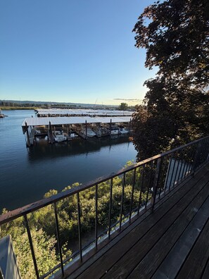 A docked boat marina with multiple boats, a clear sky, and a view of a distant cityscape. - Riverfront Retreat - Waterfront Views & 2 Decks (Portland)