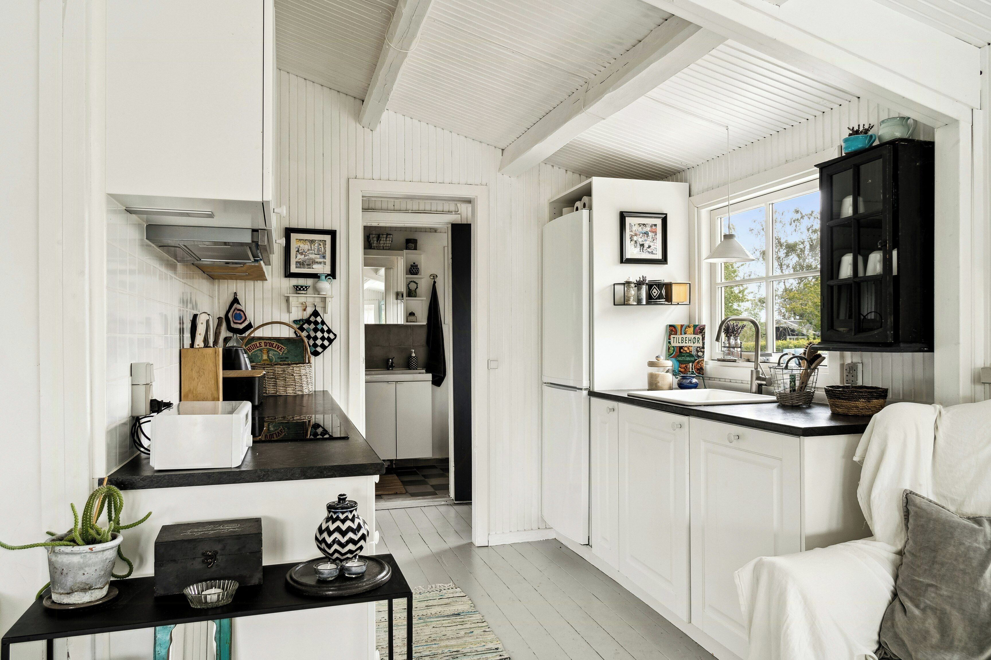 A kitchen with white cabinetry, a black countertop, and a window.