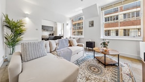 Ein modernes Wohnzimmer mit einer Couch, einem Couchtisch und großen Fenstern.