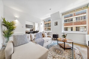 Ein modernes Wohnzimmer mit einer Couch, einem Couchtisch und großen Fenstern.