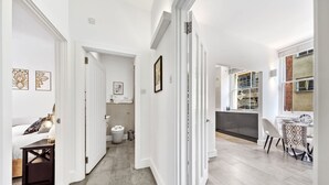 Ein modernes Interieur mit einer Diele, die zu einem Badezimmer, einem Essbereich und einer Küche führt.