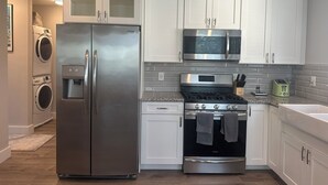 A modern kitchen with stainless steel appliances, white cabinetry, and a granite countertop.