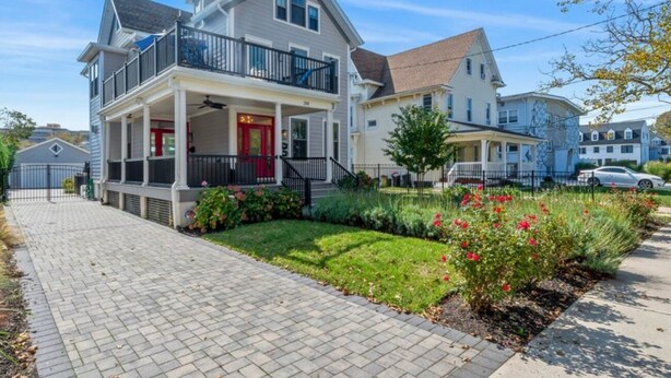 A two-story residential house with a balcony, a front porch, and a well-maintained garden.
