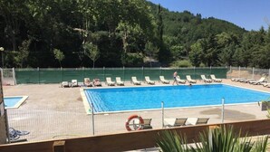 A swimming pool with lounge chairs, a lifebuoy, and a grassy area. - Camping 3 étoiles - Piscine  - ccbgdcd (Rennes-les-Bains)