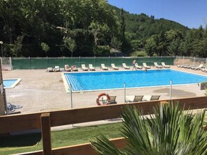 Ein Schwimmbecken mit Liegestühlen, einem Rettungsring und einer Rasenfläche.