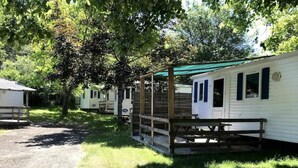 A row of mobile homes with a covered walkway, surrounded by trees. - Camping 3 étoiles - Piscine  - ccbgdcd (Rennes-les-Bains)