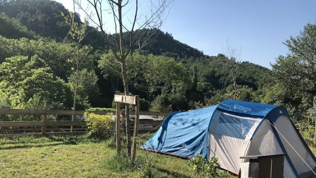A camping site with a tent, a wooden fence, and a forested hill in the background. - Camping 3 étoiles - Piscine  - ccbgdcd (Rennes-les-Bains)