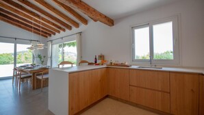 A modern kitchen with wooden beams, a dining area, and large windows.