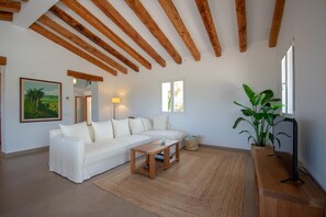 Un soggiorno con un divano bianco, un tavolino in legno e una pianta grande.