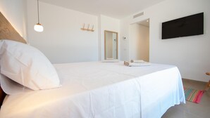 A bedroom with a bed, a television, a mirror, and a door.
