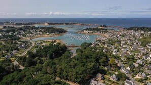 An aerial view of a coastal town with residential areas, a marina, and a bridge connecting different parts of the town.