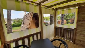 Ein überdachter Außenbereich mit Blick auf ein Holzhaus und einen umzäunten Garten.