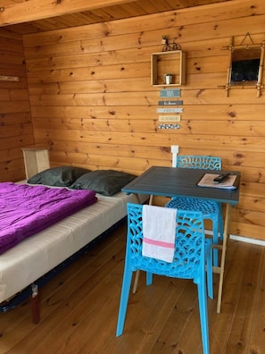A wooden cabin room with a bed, a table, and chairs.