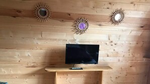 Una habitación con paredes de paneles de madera, un televisor montado sobre un soporte de madera y una colcha morada.