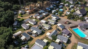 An aerial view of a mobile home park with compact housing units, a swimming pool, and a central road.