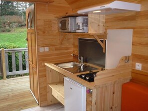 A compact wooden kitchen with a sink, stove, and microwave. - Camping 3 étoiles - Piscine  - ccbgchd (Perros-Guirec)