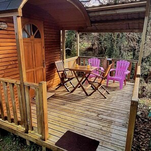 A wooden deck with a table and chairs, a covered area, and a wooden door. - Camping 3 étoiles - Piscine  - ccbgchd (Perros-Guirec)