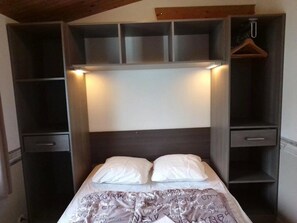 Ein Schlafzimmer mit Bett, Kleiderschrank und Ablagefläche.