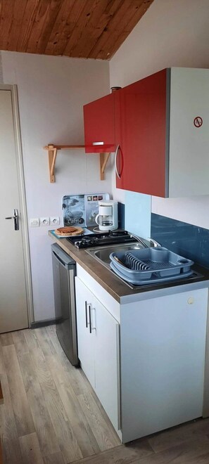 Una cocina compacta con estufa, lavaplatos y armarios.