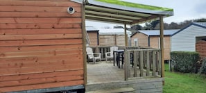 A wooden deck with a covered seating area and a small table. - Camping 3 étoiles - Piscine  - ccbgchf (Perros-Guirec)