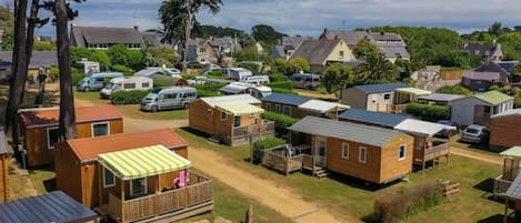 A campsite with multiple wooden cabins, some with attached porches, and a few with attached vehicles.