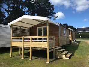 Ein Holz-Mobilheim mit überdachter Terrasse und kleiner Veranda.