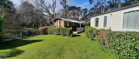 Una casa móvil con porche, rodeada de un césped cuidado y árboles frondosos.