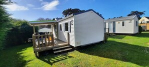A mobile home with a porch and a covered outdoor seating area. - Camping 3 étoiles - Piscine  - ccbgcia (Perros-Guirec)