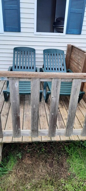 A wooden deck with a bench and chairs, a wooden fence, and a house with shutters. - Camping 3 étoiles - Piscine  - ccbgcib (Perros-Guirec)