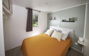 Ein Schlafzimmer mit einem Bett, einem Fenster mit Vorhängen, einem Regal mit Dekoration und einem Nachttisch.