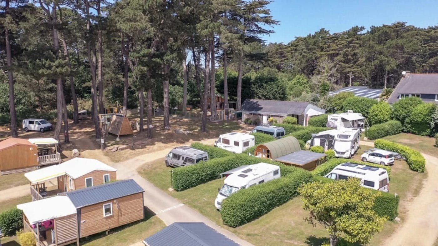 A campground with RVs and mobile homes, surrounded by trees and greenery.