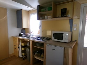 A compact kitchen with a microwave, gas stove, and a small refrigerator. - Camping 3 étoiles - ccbgdfi (Neuwiller-lès-Saverne)