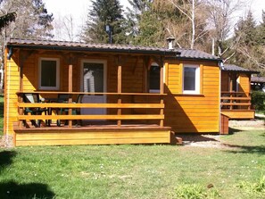 A wooden cabin with a porch, a window, and a door. - Camping 3 étoiles - ccbgdg0 (Neuwiller-lès-Saverne)