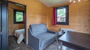 A cozy cabin interior with a sofa, a small table, and a window with a view of a house.