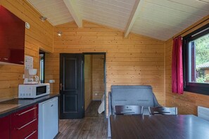 A compact room with a kitchenette, a dining table, and a sleeping area.