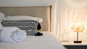 A neatly made bed with patterned pillows and a rolled towel, a bedside lamp, and a headboard. - Le Nid d'Alspach: Romantic Retreat in Colmar (Colmar)