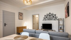 A modern living room with a sofa, TV, and artwork. - Le Nid d'Alspach: Romantic Retreat in Colmar (Colmar)