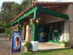 Ein Gebäude mit einer Rezeption, grünen Säulen und hängenden Blumenampeln.