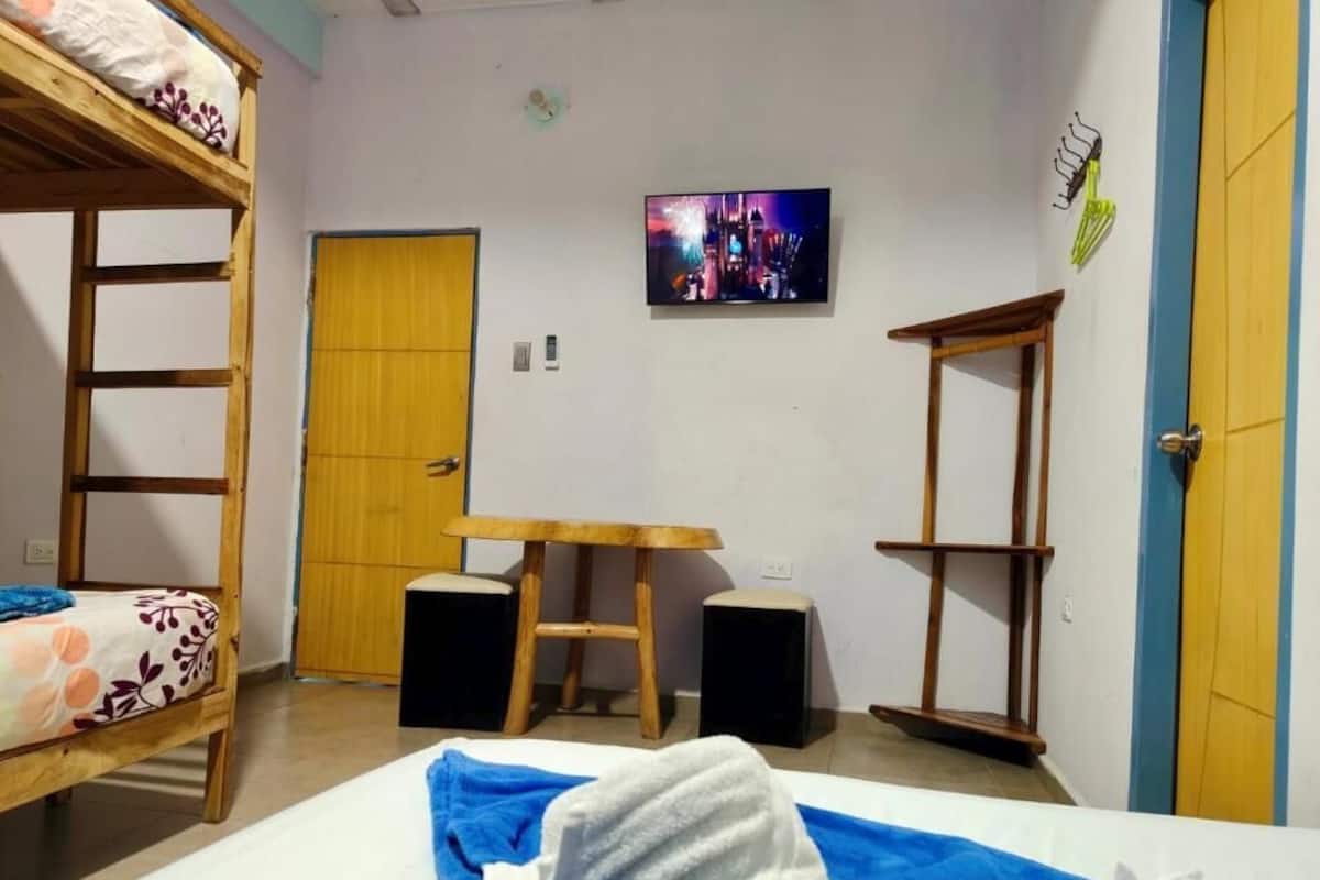 A room with bunk beds, a desk, speakers, and a TV.
