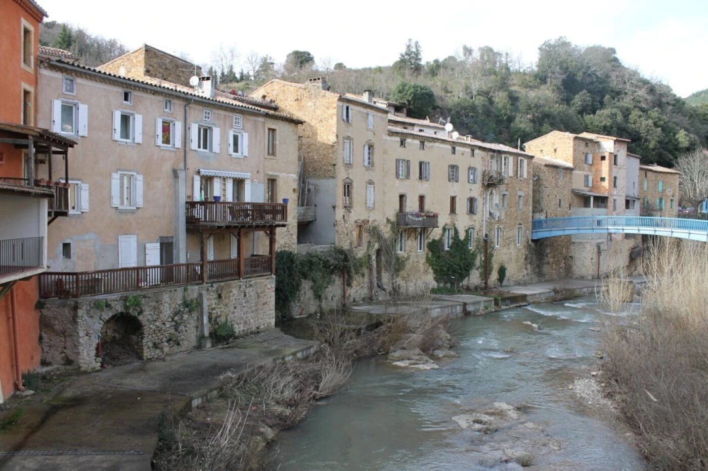 A river running through a town with stone buildings and a bridge.