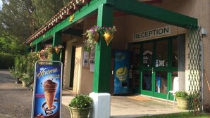Un edificio con área de recepción, pilares verdes y macetas colgantes.