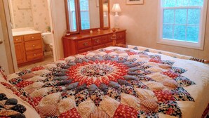 Une chambre à coucher avec un grand lit, une commode, un miroir, une fenêtre et une porte.