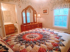 Ein Schlafzimmer mit einem großen Bett, einem Schminktisch, einem Spiegel, einem Fenster und einer Tür.