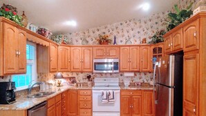 Une cuisine avec des meubles de rangement en bois, un four blanc, un four à micro-ondes et un réfrigérateur.
