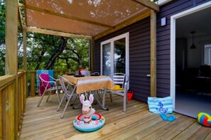 Eine Holzterrasse mit Tisch und Stühlen, ein kleiner aufblasbarer Pool und eine Tür, die in einen Innenraum führt.