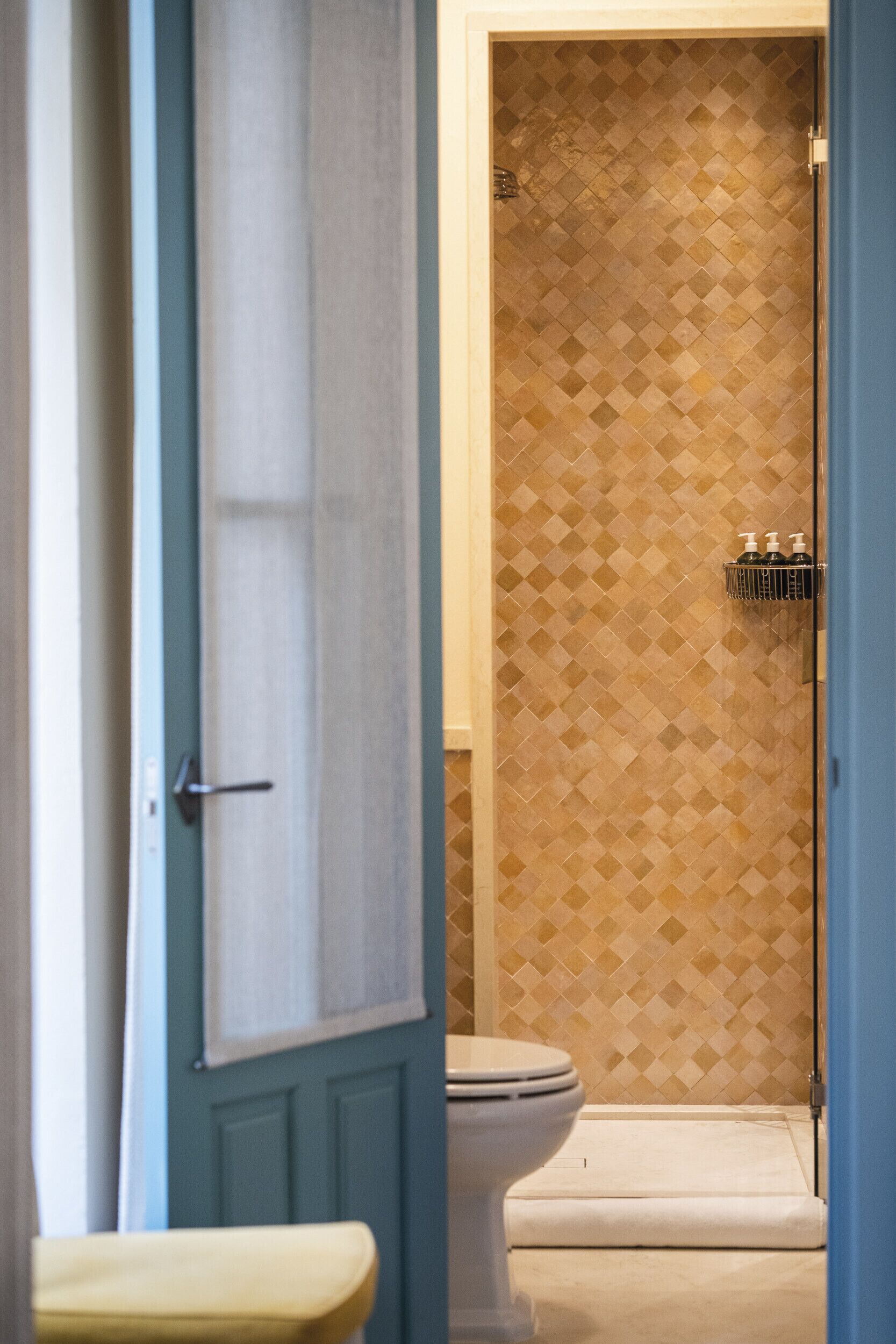 A bathroom with a patterned wall, a toilet, and a shower area.