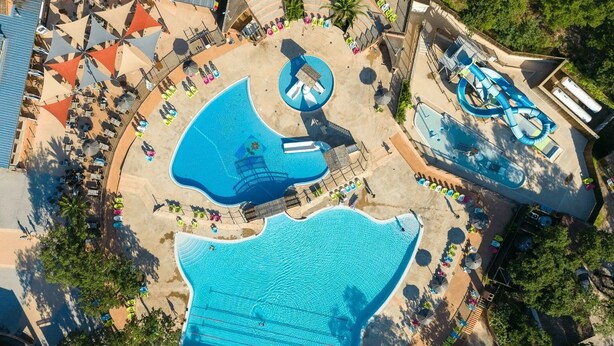 Ein weitläufiger Außenpoolbereich mit mehreren Pools, Liegestühlen und Sonnenschirmen.